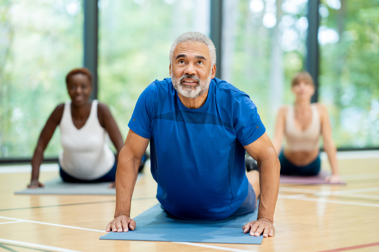 A diverse group of adults follows their instructor in a yoga pose.