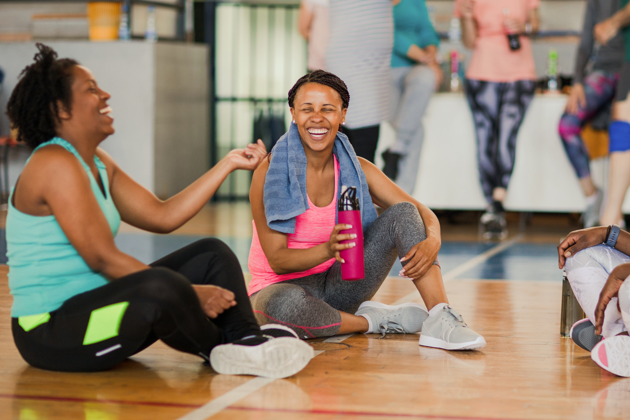 Friends sitting on the floor and talking after dance class at the fitness center.