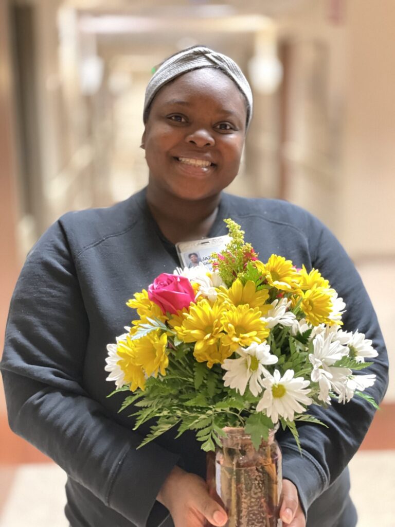 Close up of Jazmaine smiling, holding flowers.