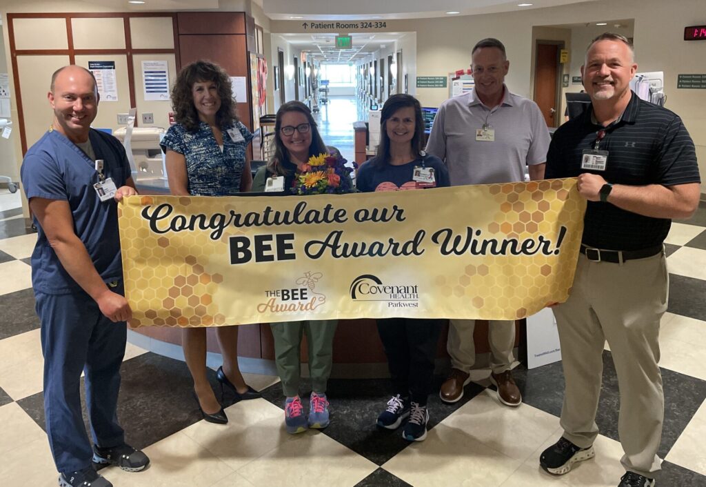 Group of smiling people holding a yellow BEE Award banner.