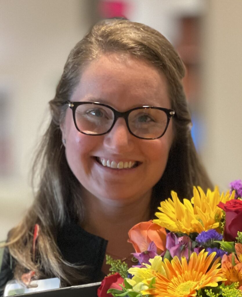Smiling woman with brown hair and glasses.