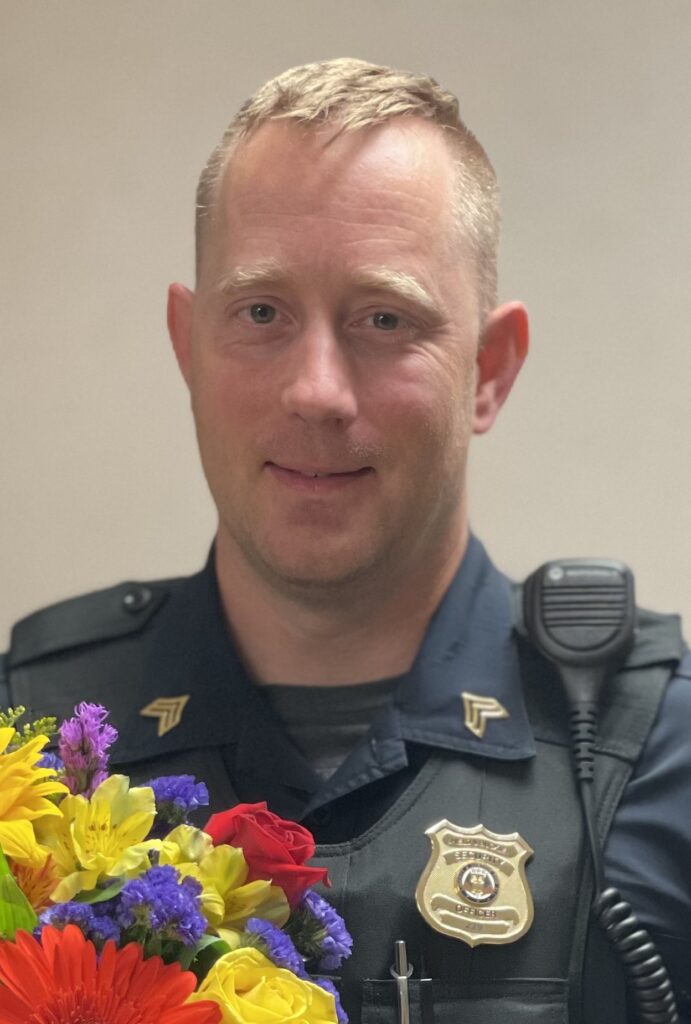 Blonde man with security uniform on holding flowers.