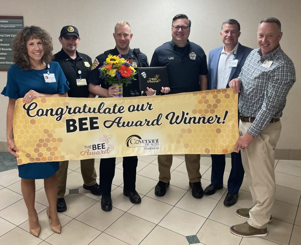 Group of six smiling people holding BEE Award Banner.