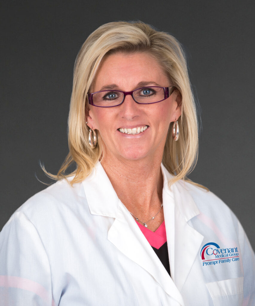 A woman with blonde hair and glasses smiles, wearing a white lab coat with a Covenant Medical Group Prompt Family Care logo, against a plain dark background.