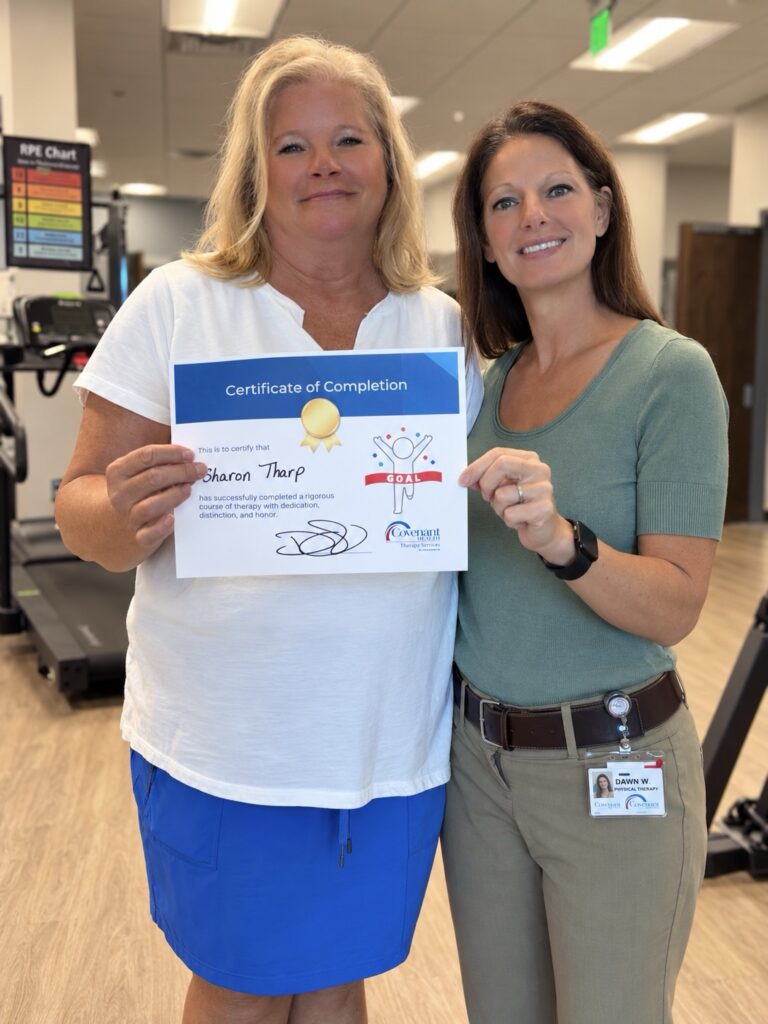 Two women hold a Covenant Health certificate of completion for Sharon Tharp, with a physical therapist wearing an ID badge standing on the right.