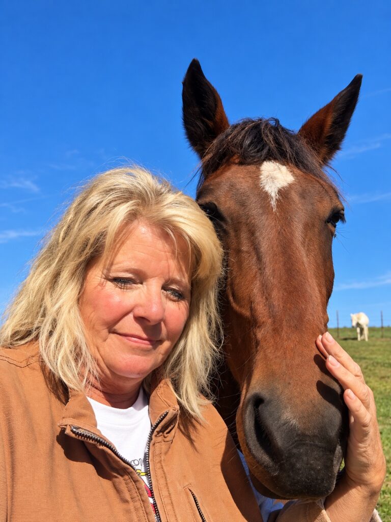 A woman smiling while resting her head against a brown horse with a white star on its forehead.